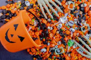 Table with Halloween candy pouring out of a pumpkin