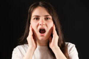 woman holding her jaw and opening her mouth