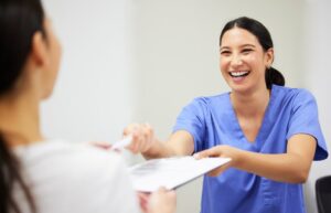 Dental staff member handing paperwork to patient
